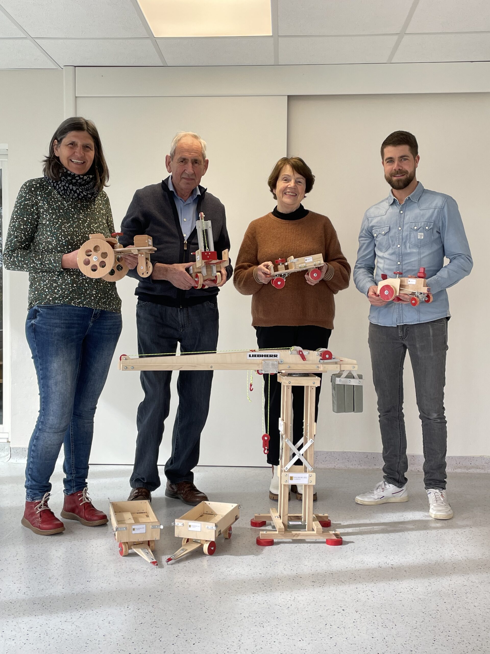 Vier erwachsene Menschen halten Holzspielzeug in den Händen